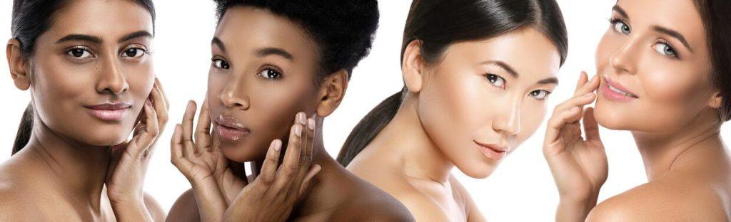 Four women with diverse skin tones and healthy complexions gently touching their faces,