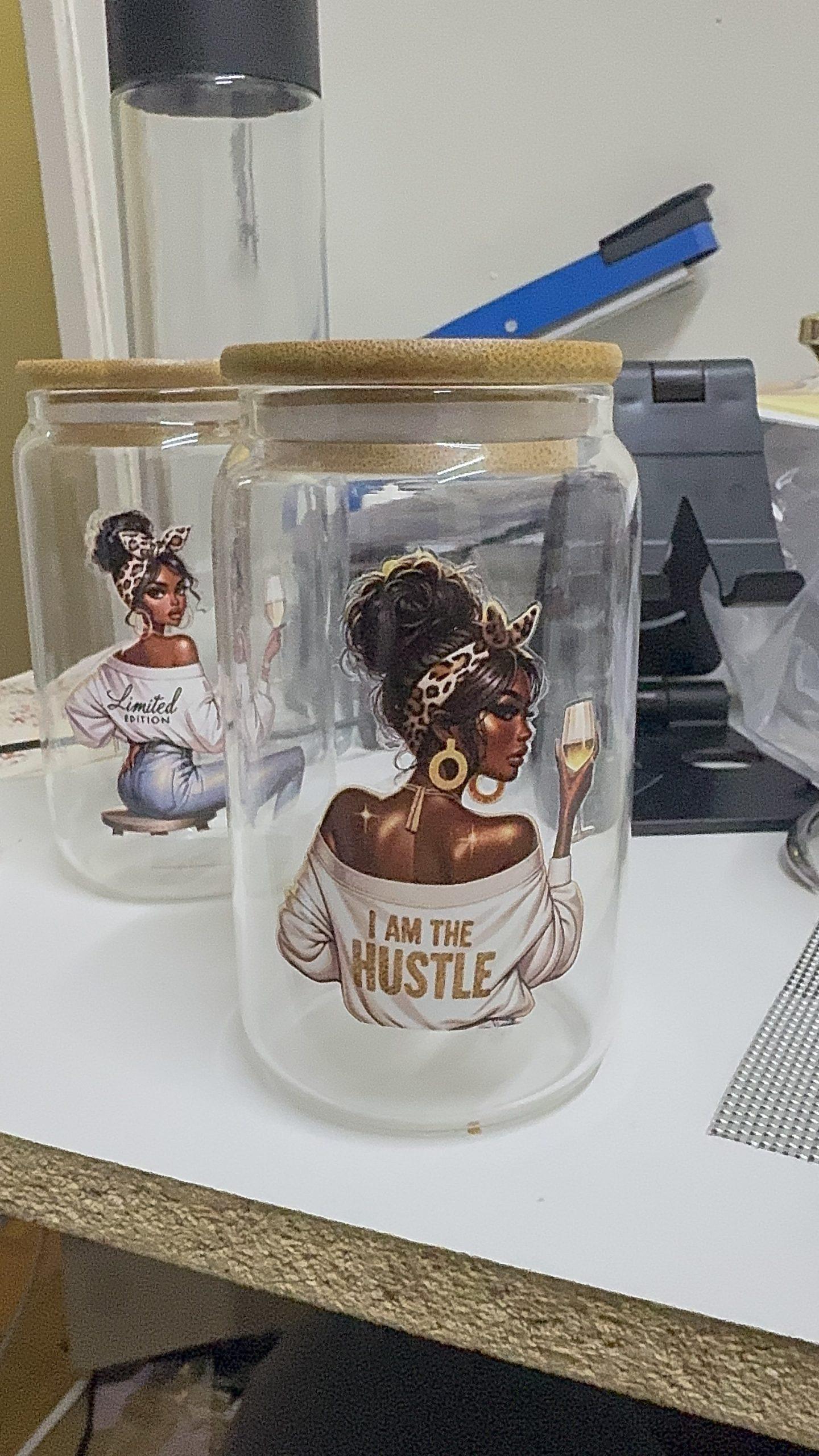 Two clear glass jars with wooden lids; one with a "Limited Edition" graphic and the other with an "I Am The Hustle" graphic.